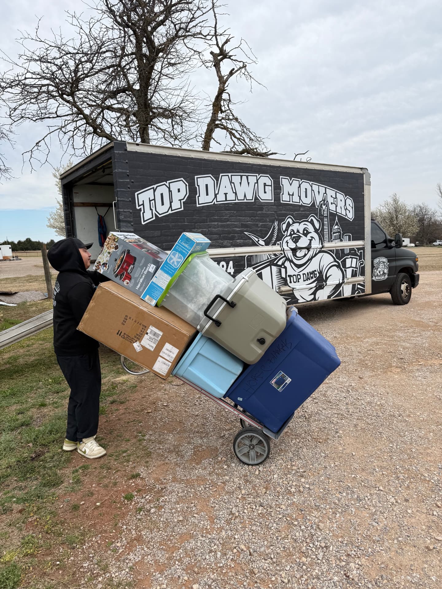 Top Dawg Movers crew member rolling a loaded dolly to the branded moving truck